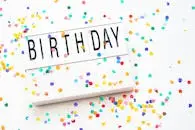 A vibrant birthday celebration background with colorful confetti and a birthday sign.