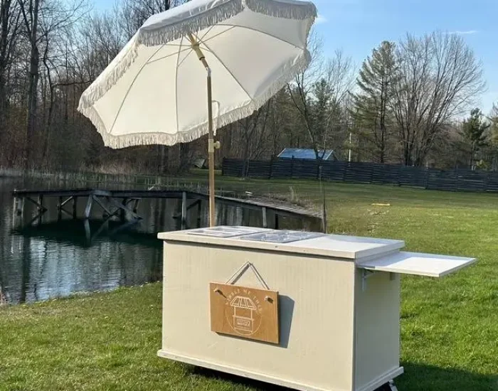 white cart, white top, side up, umbrella angled by pond white cart, white top, side up, umbrella angled by pond